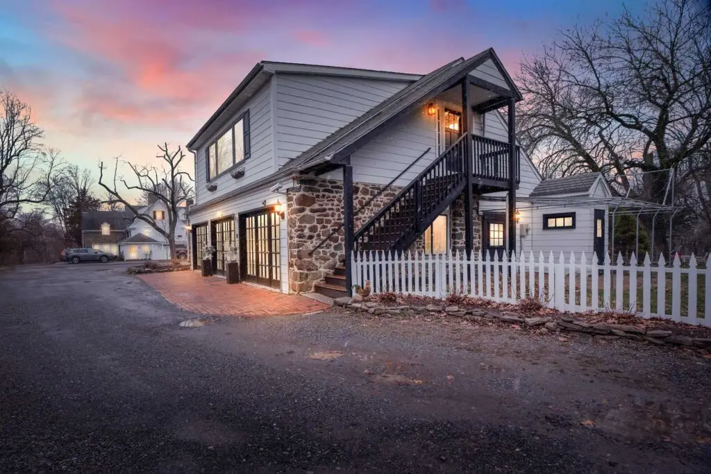 The carriage house at Chimney Hill Estate glowing at dusk beneath a pink and purple sunset sky.