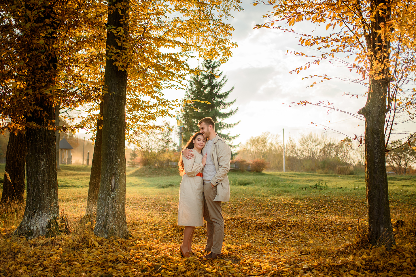 Young couple in love holding hands and walking through a park on a sunny autumn day
