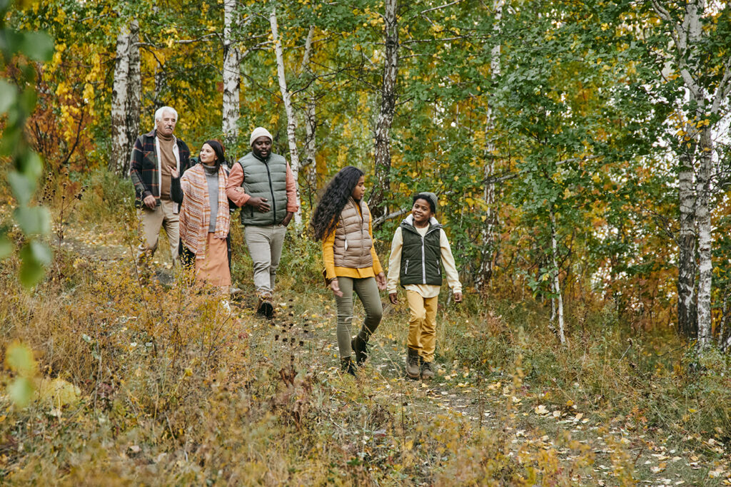 Group of people walking through a wooded area.